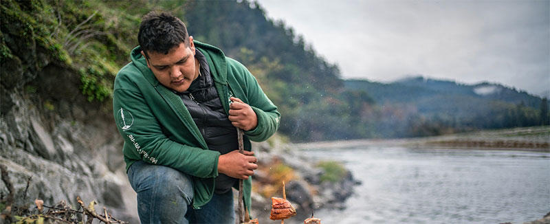 Indigenous young man preparing food outside