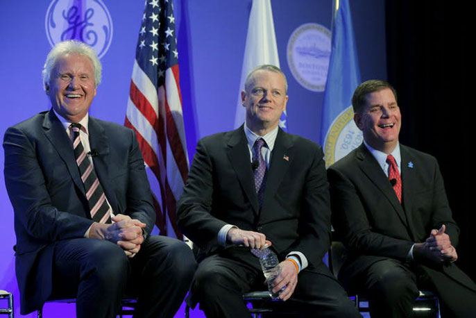 Three men sit on a stage