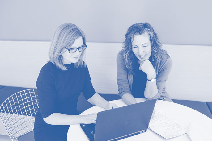 Laura Schmidt and Cristin Kearns work together on a laptop