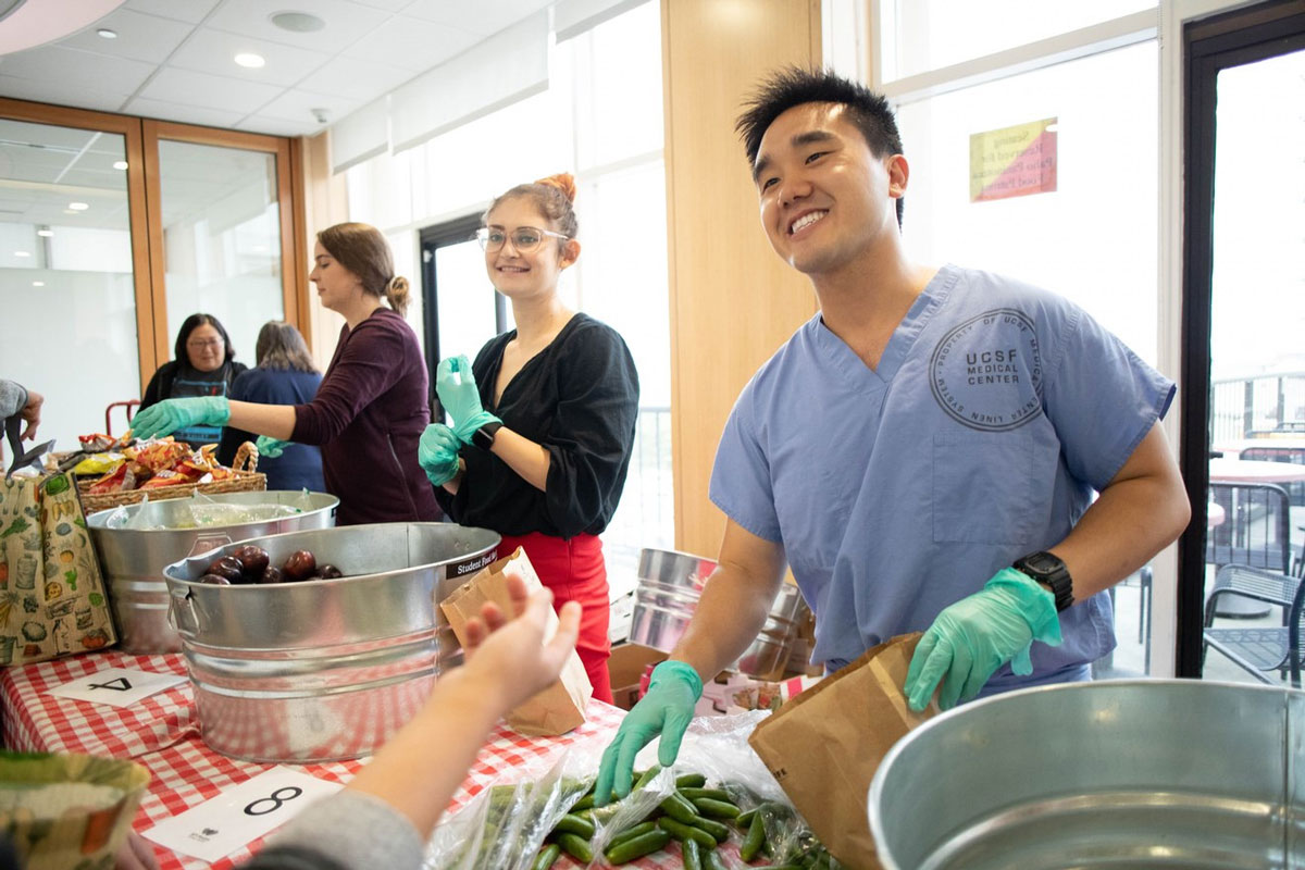 Jerry Liu at a volunteer event handing out foot in medical scrubs