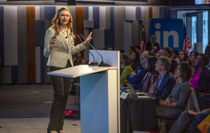 Katie Murphy presents at the podium at Grad Slam side angle