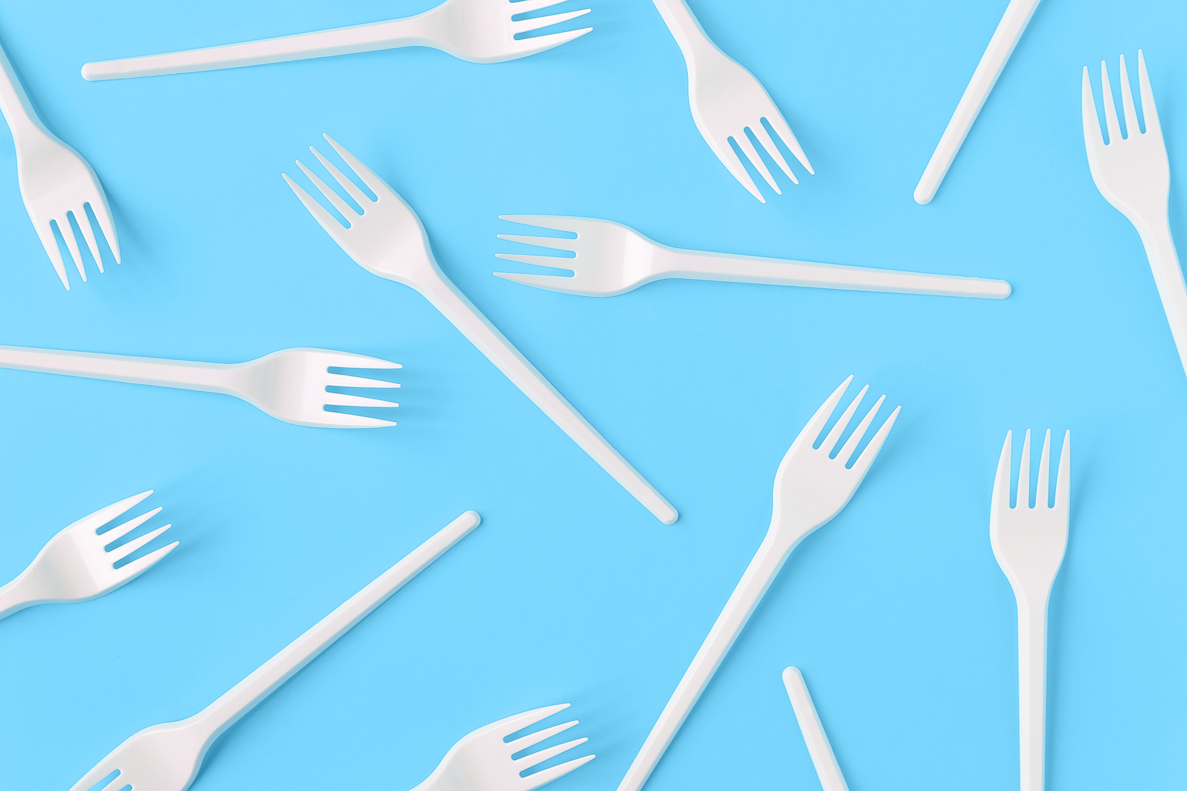 Single-use plastic forks on a blue background