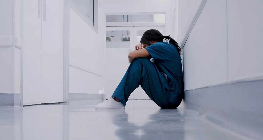 Health care worker sitting on ground frustrated