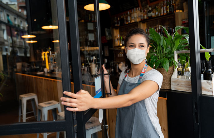 Woman wearing mask opens cafe door
