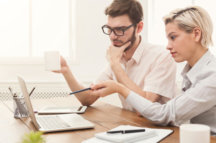 Man and woman stare at a computer