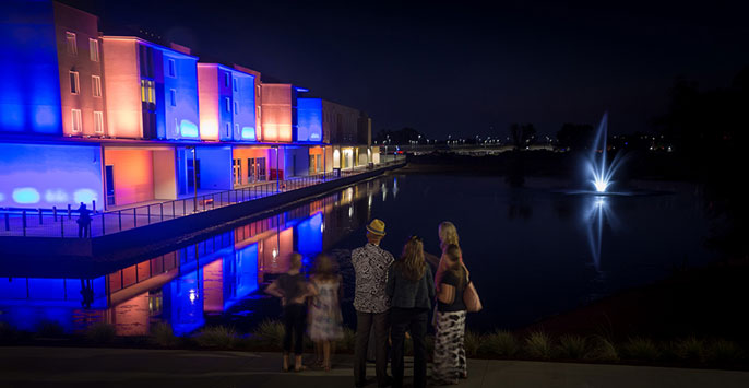 Small group looks on at new UC Merced buildings at night