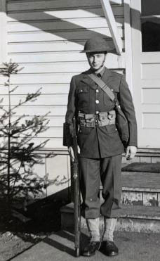 Young Milton in uniform in front of house