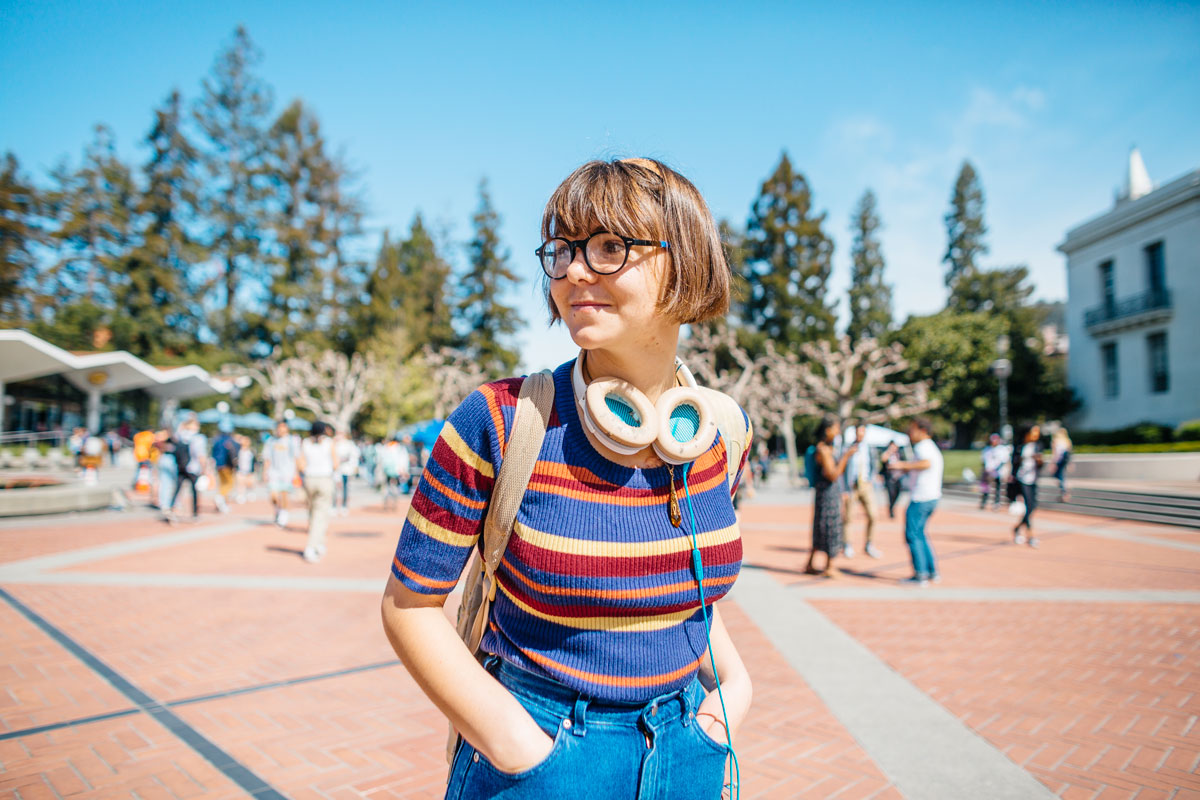 Female student in sweater looks around Sproul Plaza