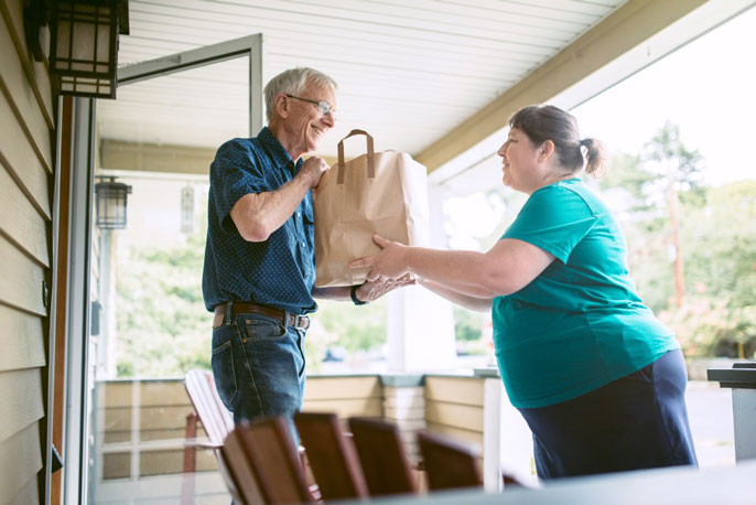 A woman brings an older man groceries