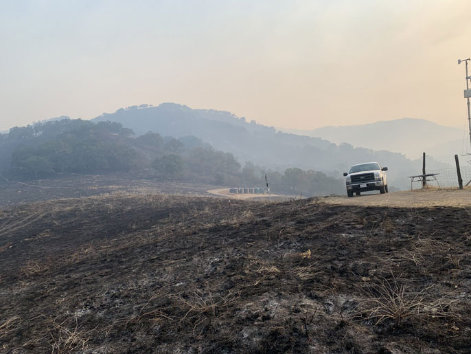 White truck near a burned out hill