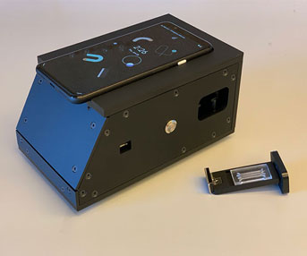 A photo shows a black box, about the size of a small loaf of bread, with an iPhone sitting on top