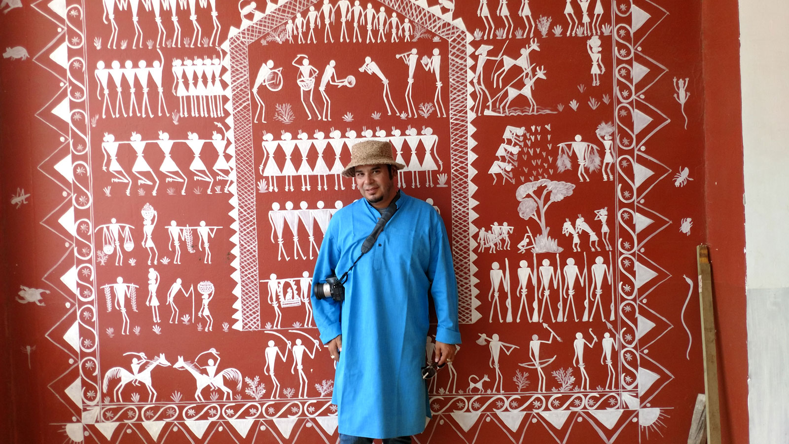 Ray Gutierrez stands in front of a mural of tribal symbols at Centurion University