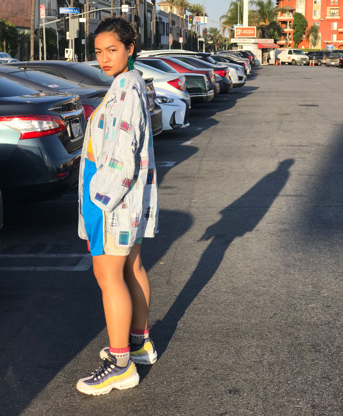 Female student in streetwear poses in parking lot