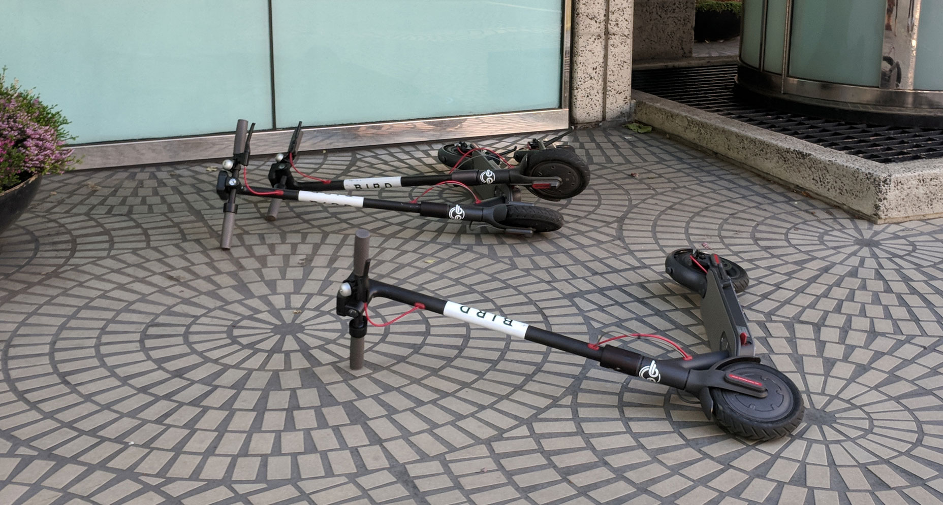 three scooters lying in the sidewalk