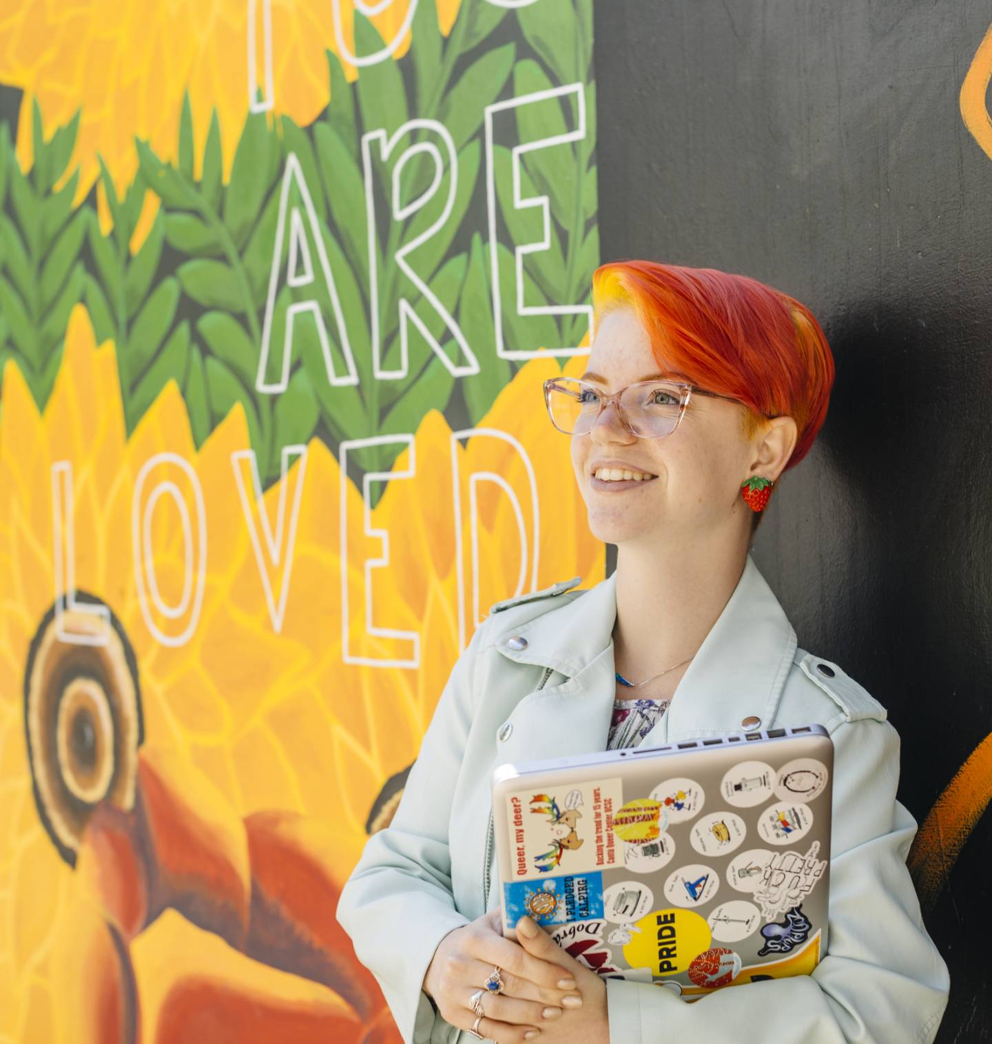 Student standing in front of mural on campus