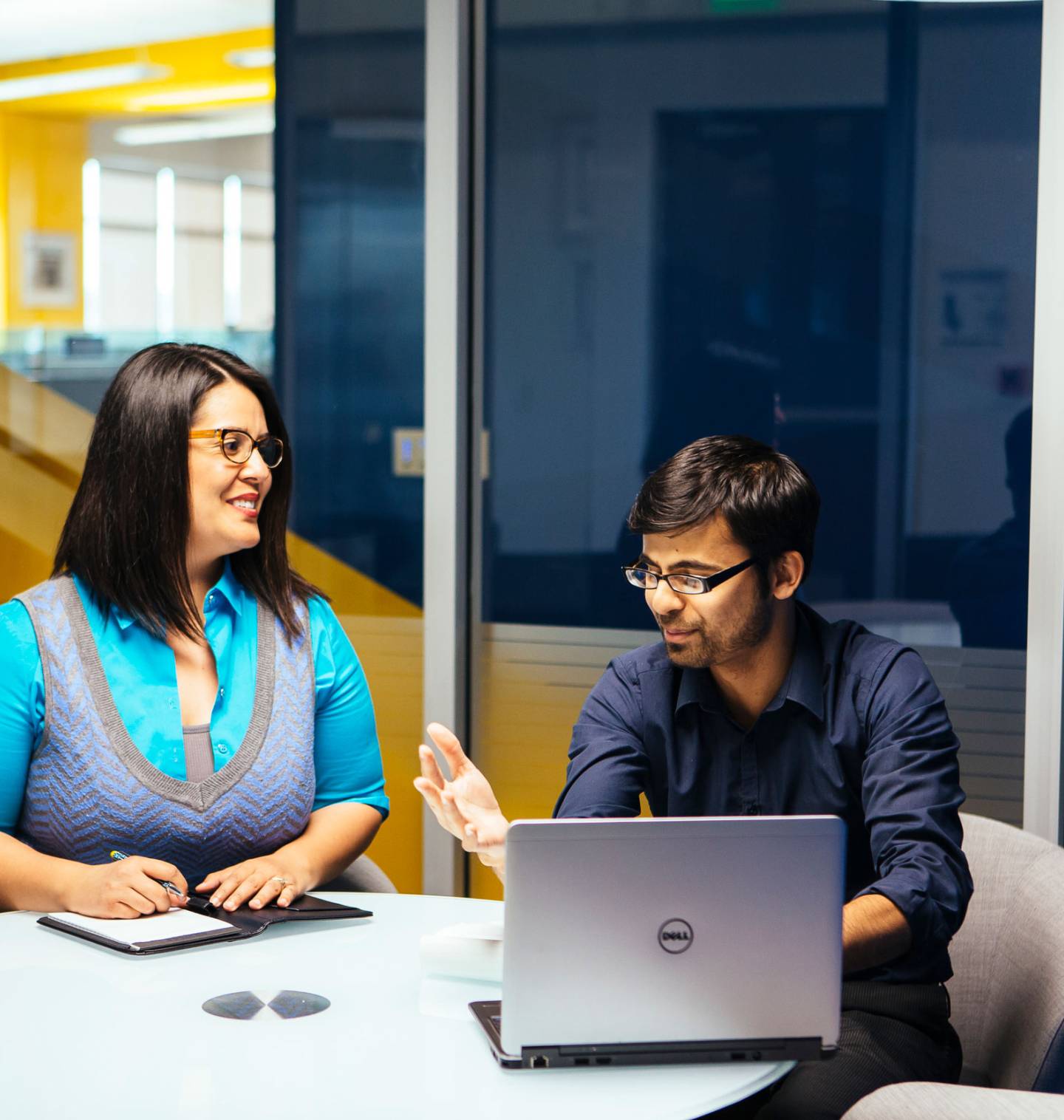 Two people meeting at a table looking at a laptop