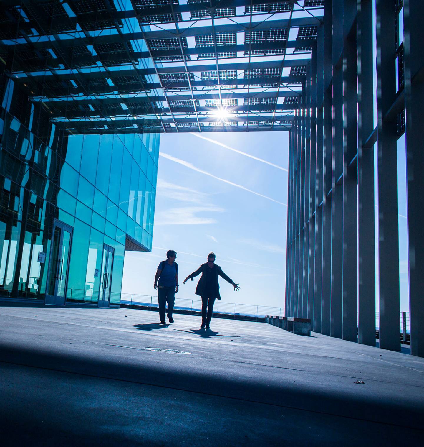 Two people walking through large hallway made of solar panels