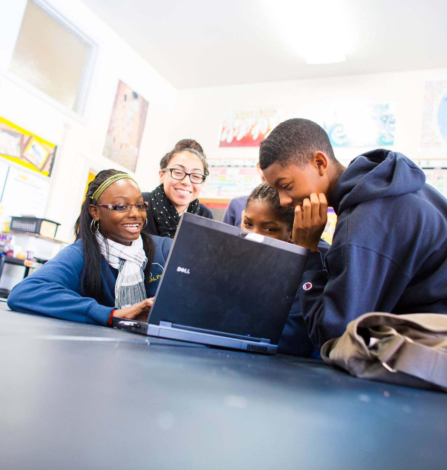 High school students gathering around a laptop to work together 