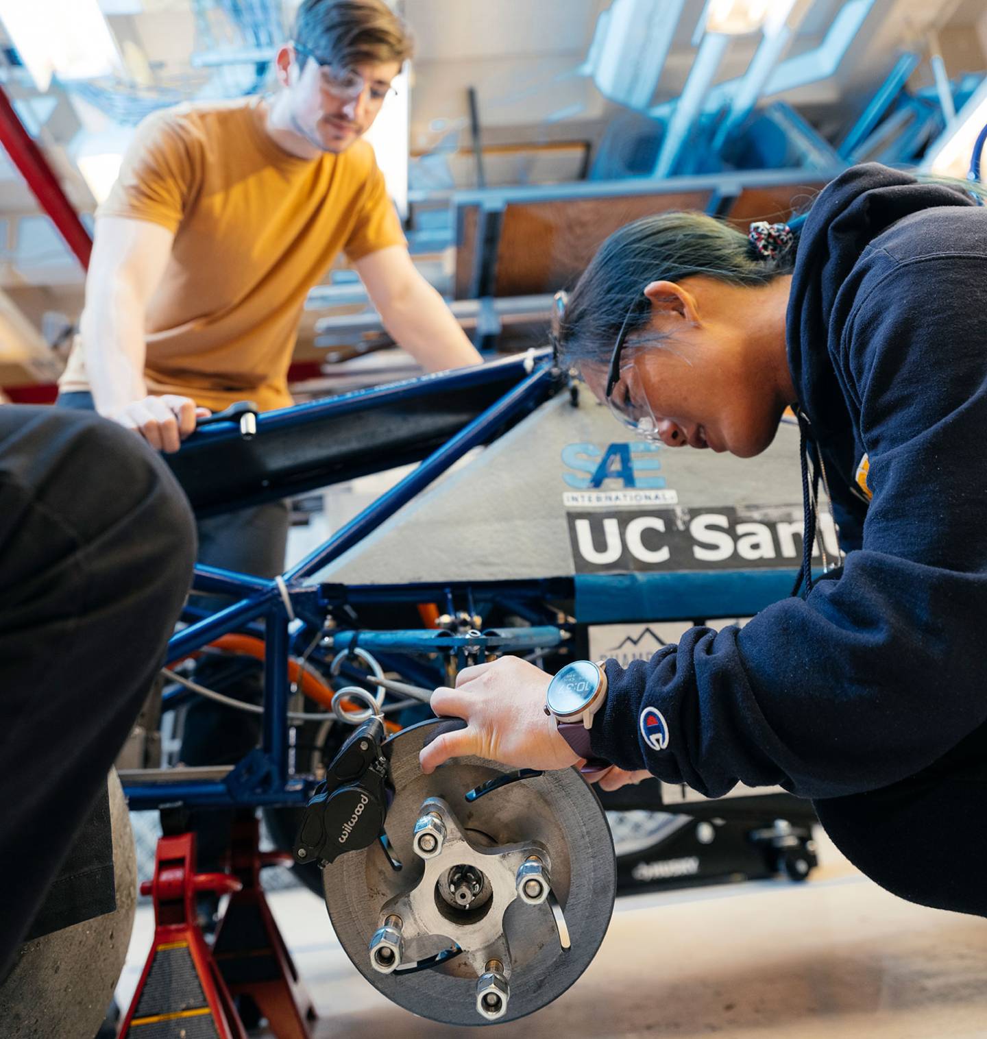 Two students working on a metal contraption. 