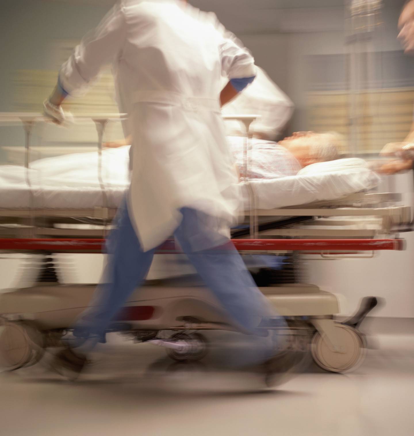 Doctors rushing a patient on a gurney down a hospital hallway