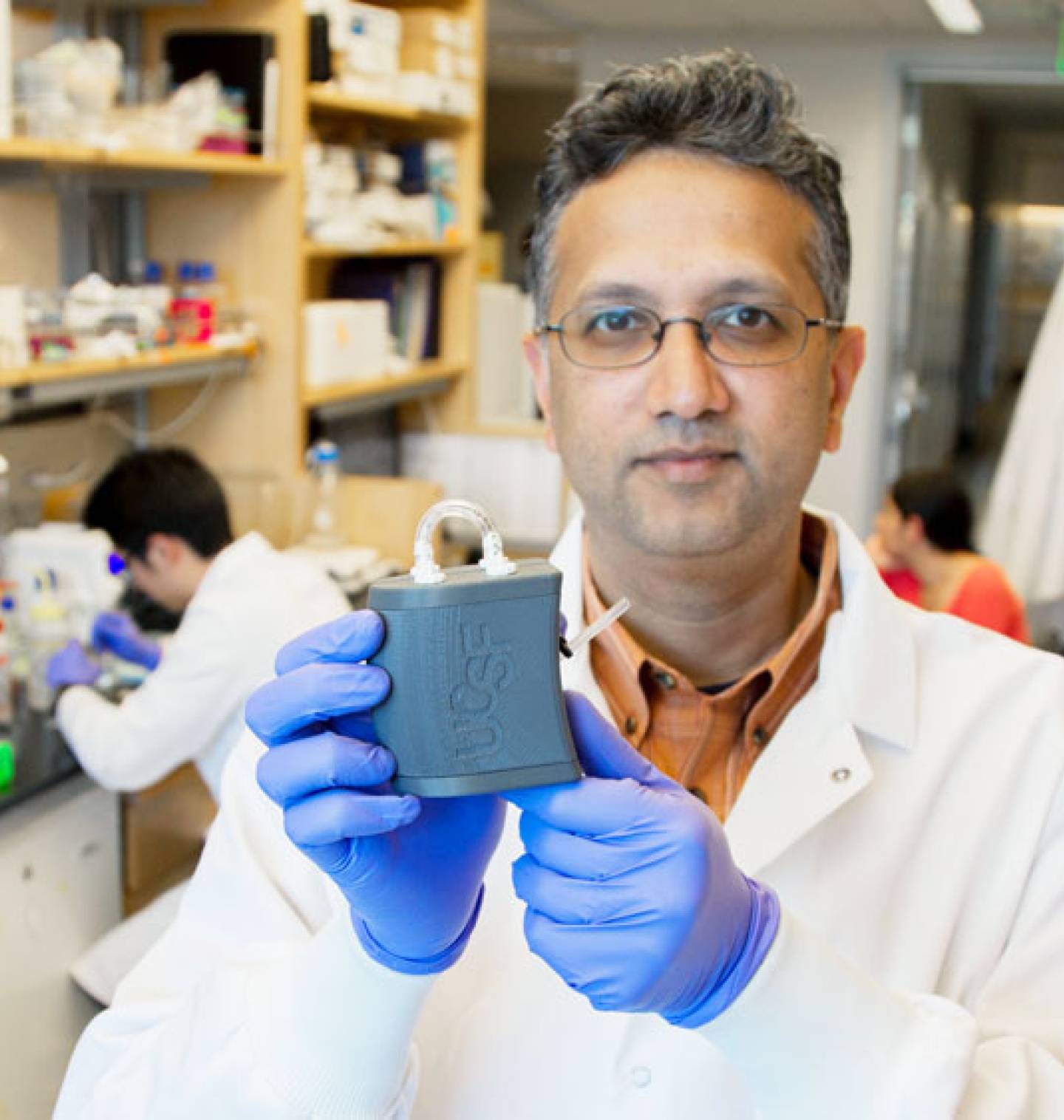 Shuvo Roy holding the artificial kidney in a lab