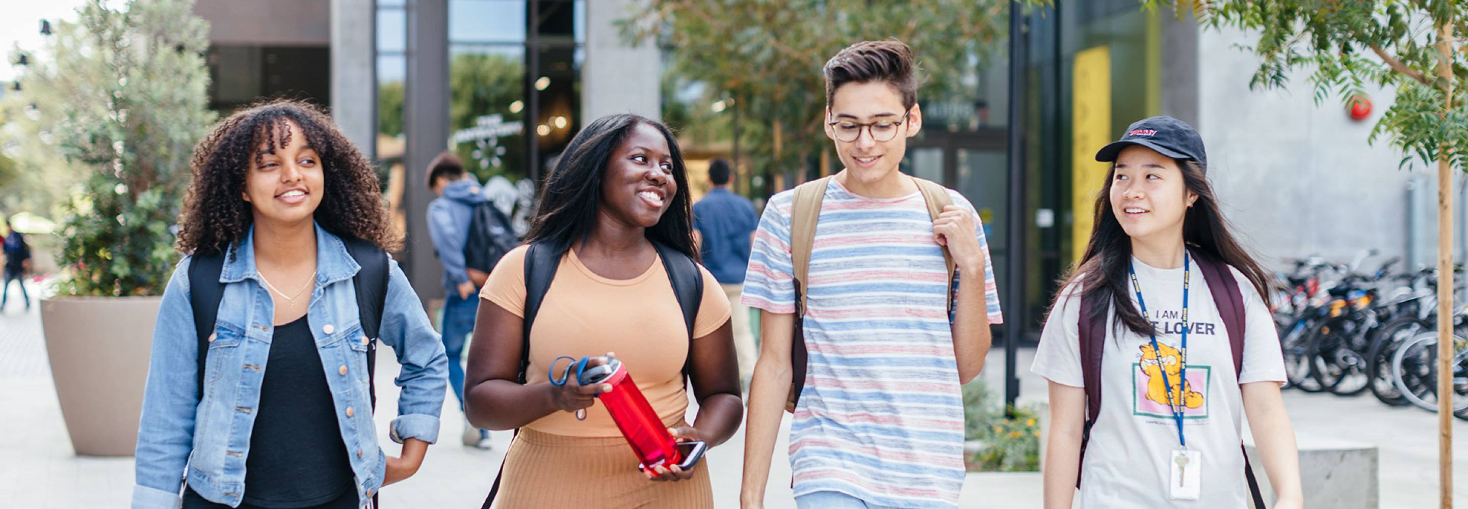 Group of four students walking on campus