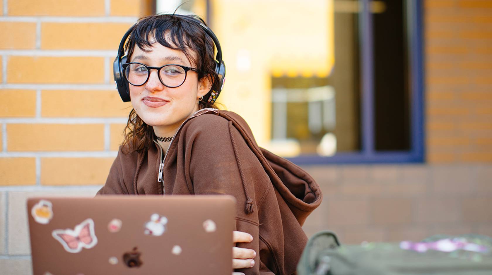 a student sits with an open laptop, smiling