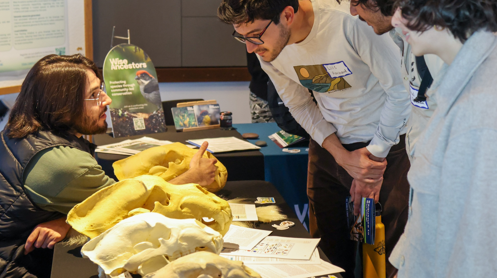 A man talking to students visiting a table that is displaying bear skulls