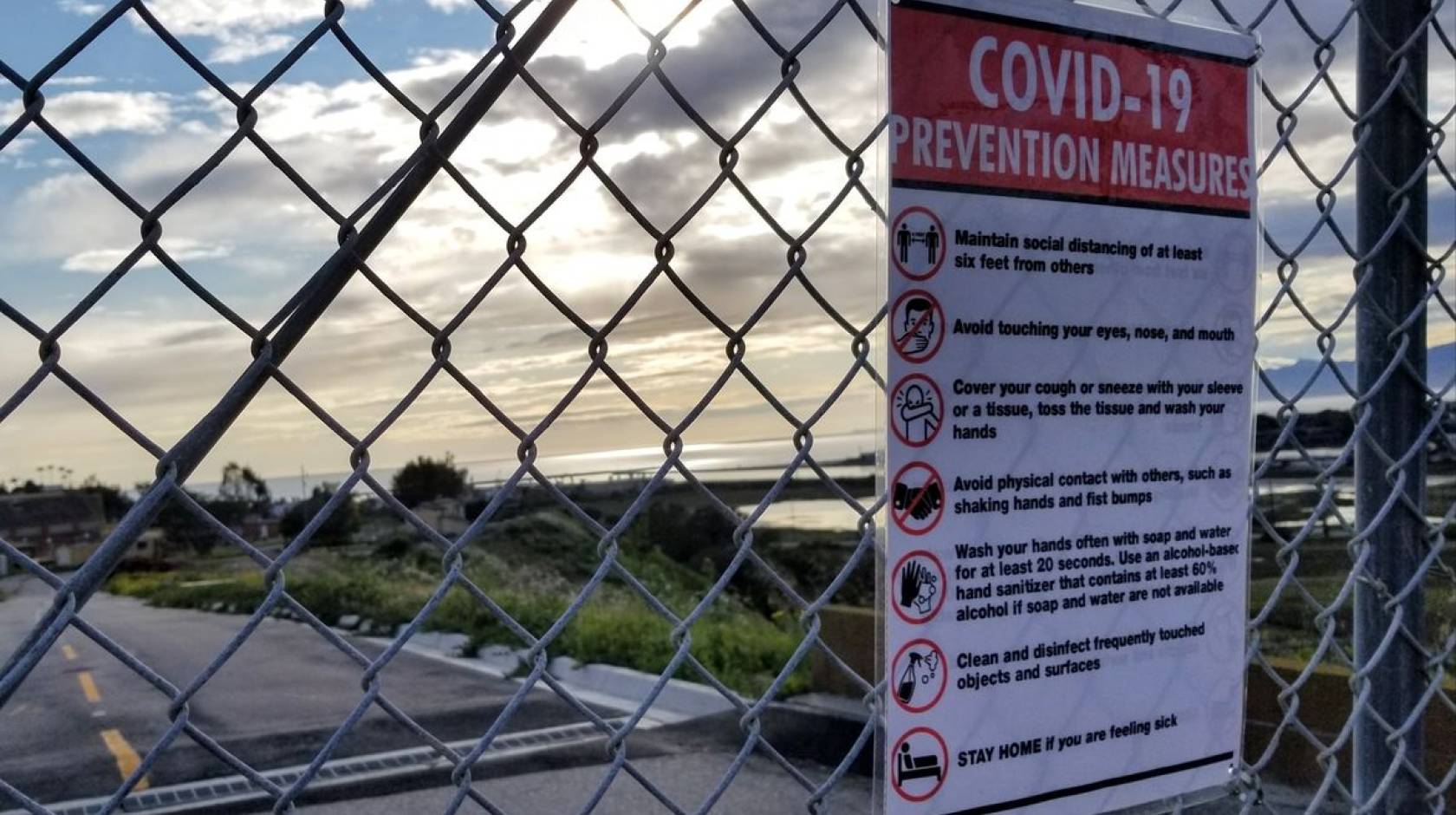 Sign on a fence about COVID-19 prevention measures