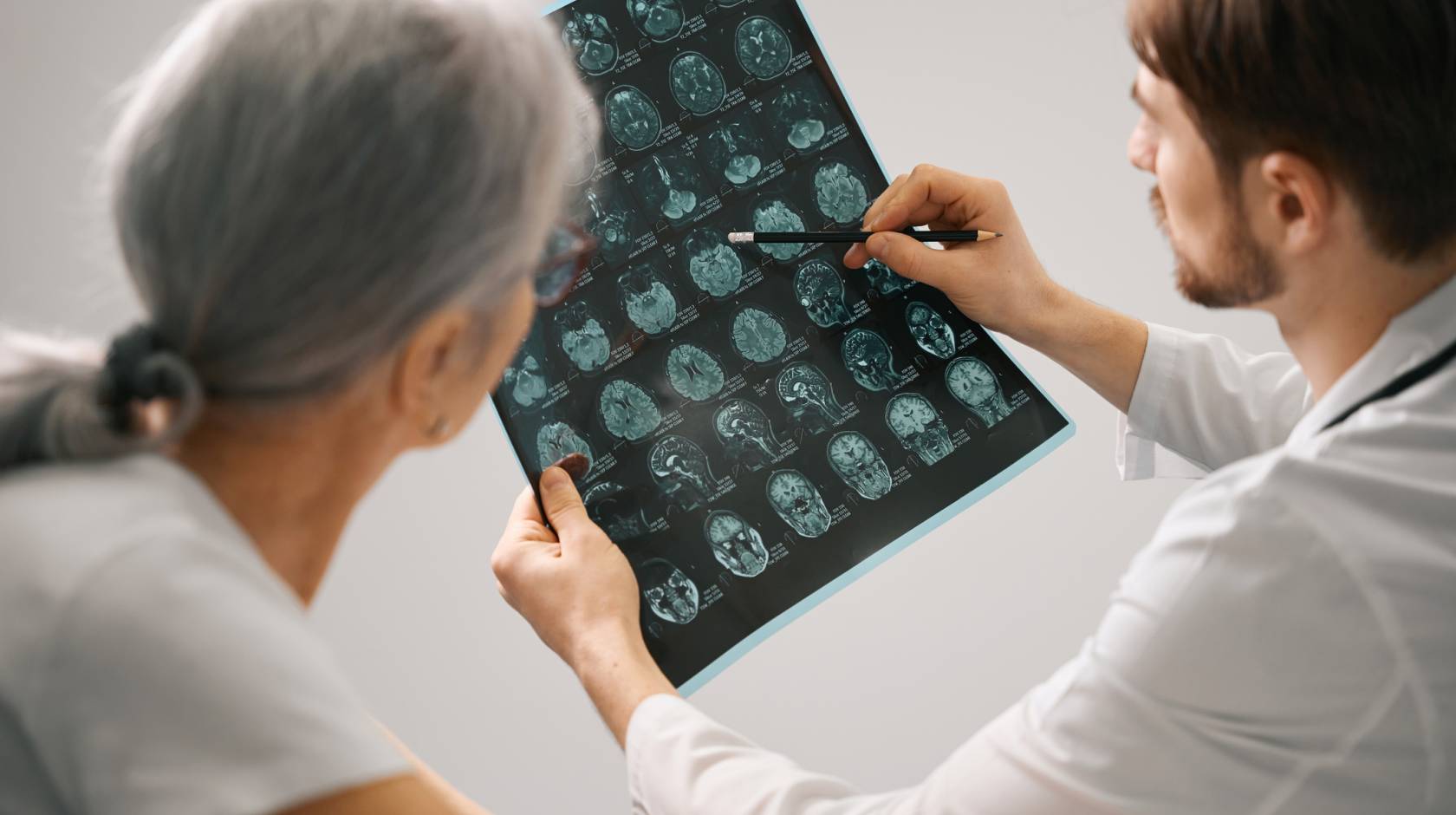 Doctor diagnostician holds an MRI scan of the brain in his hands, he consults an elderly lady