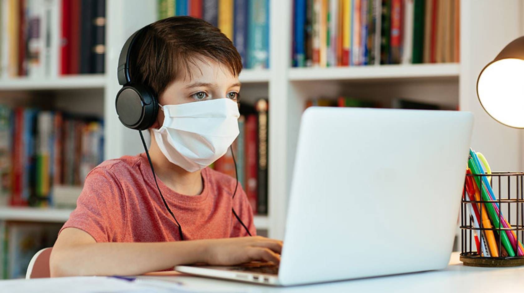 Boy in face mask working on a computer