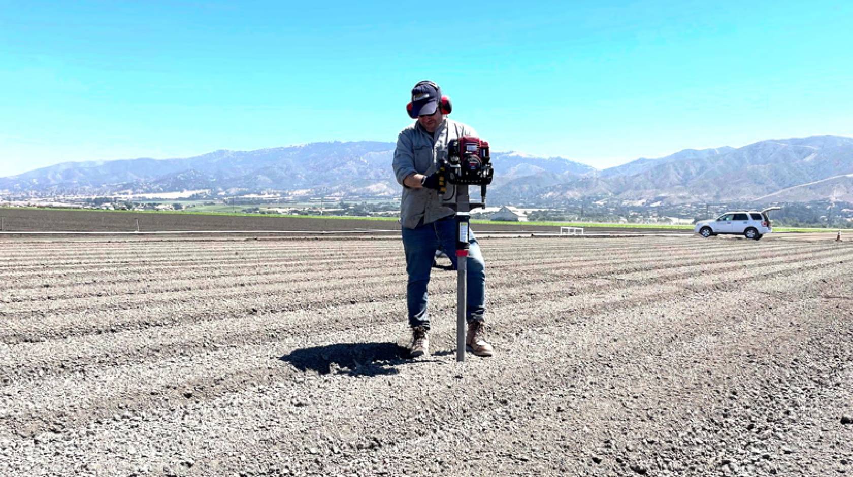 A man taking a soil sample in the middle of a dirt field