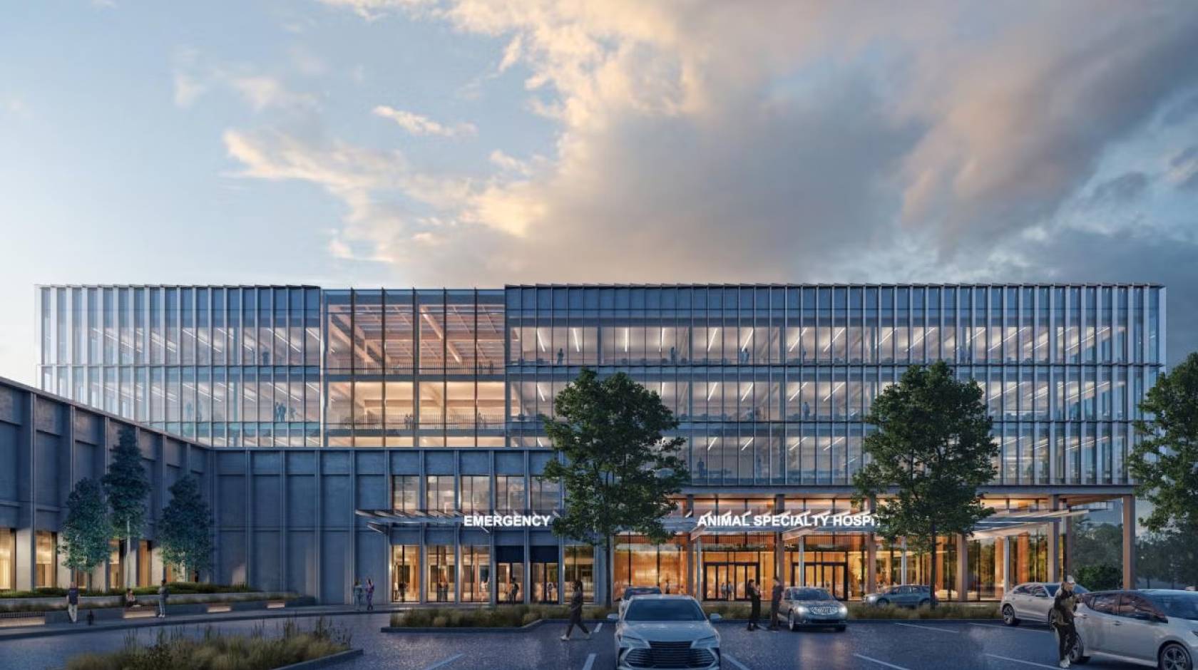 Modern glass office building at dusk with warm-lit interiors, front trees and parked car. A conceptual rendering of the entrance to the new small animal hospital