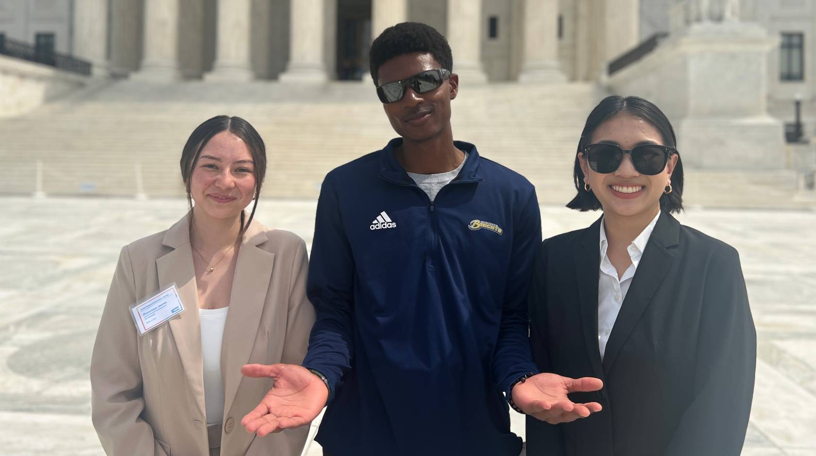 3 UCAN student ambassadors in business attire smile in front of the Capitol Building
