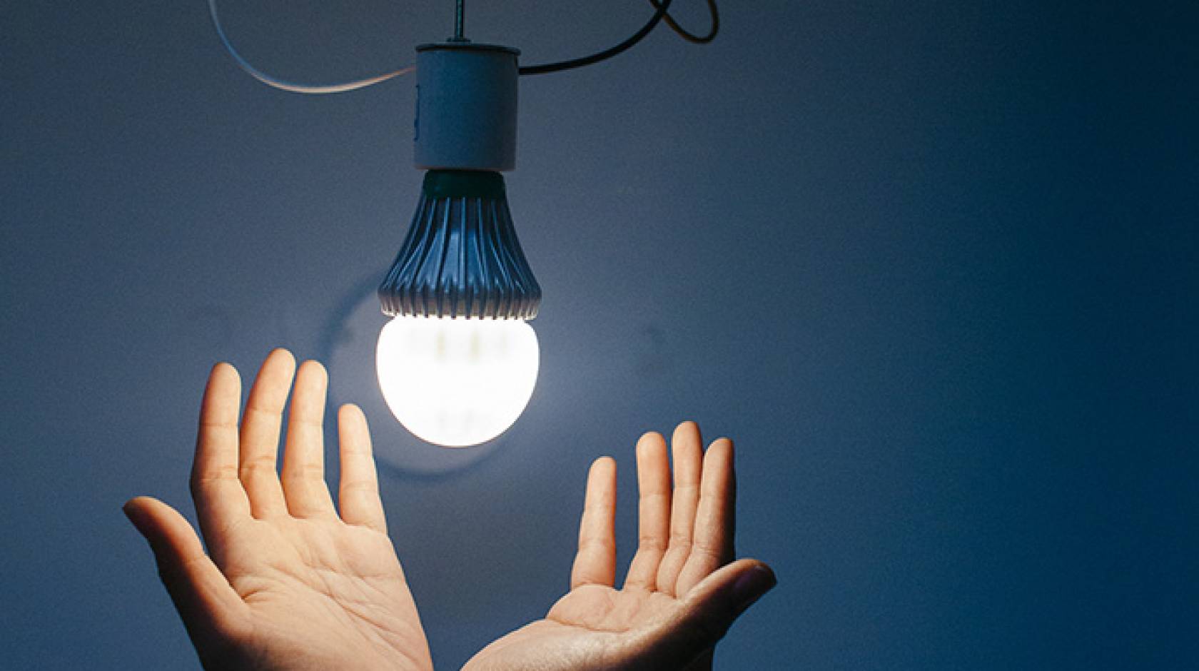 Hands below a light bulb