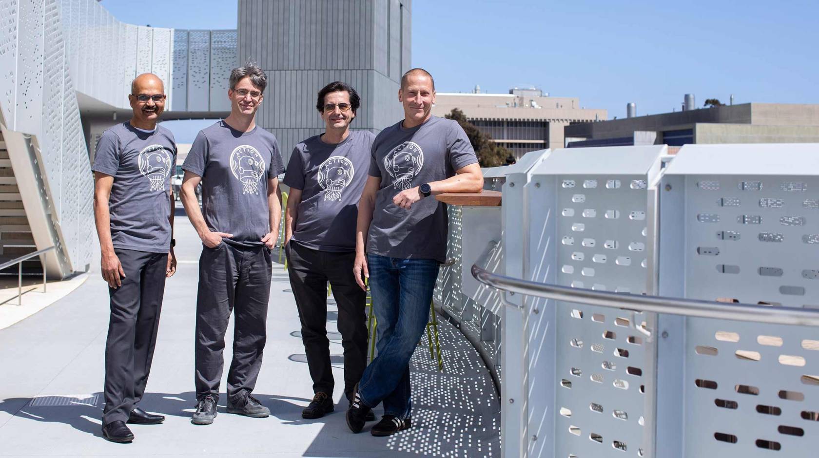 Four men in matching T-shirts standing outside