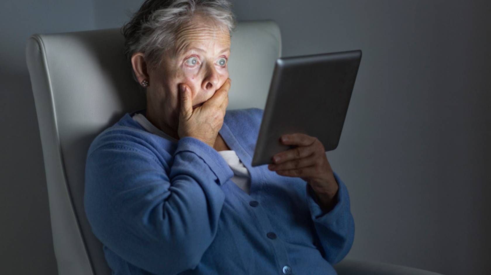 Shocked older woman watching TV on an iPad