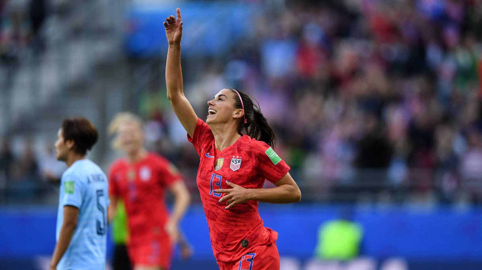 Alex Morgan pointing upward as she plays soccer for the US