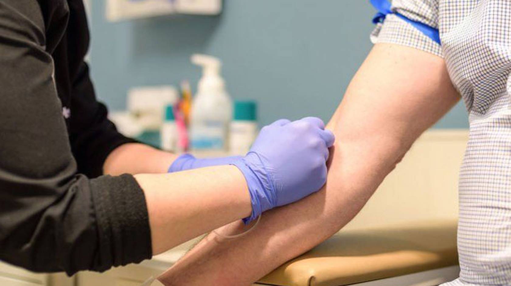 Someone taking blood from someone else in a doctor's office