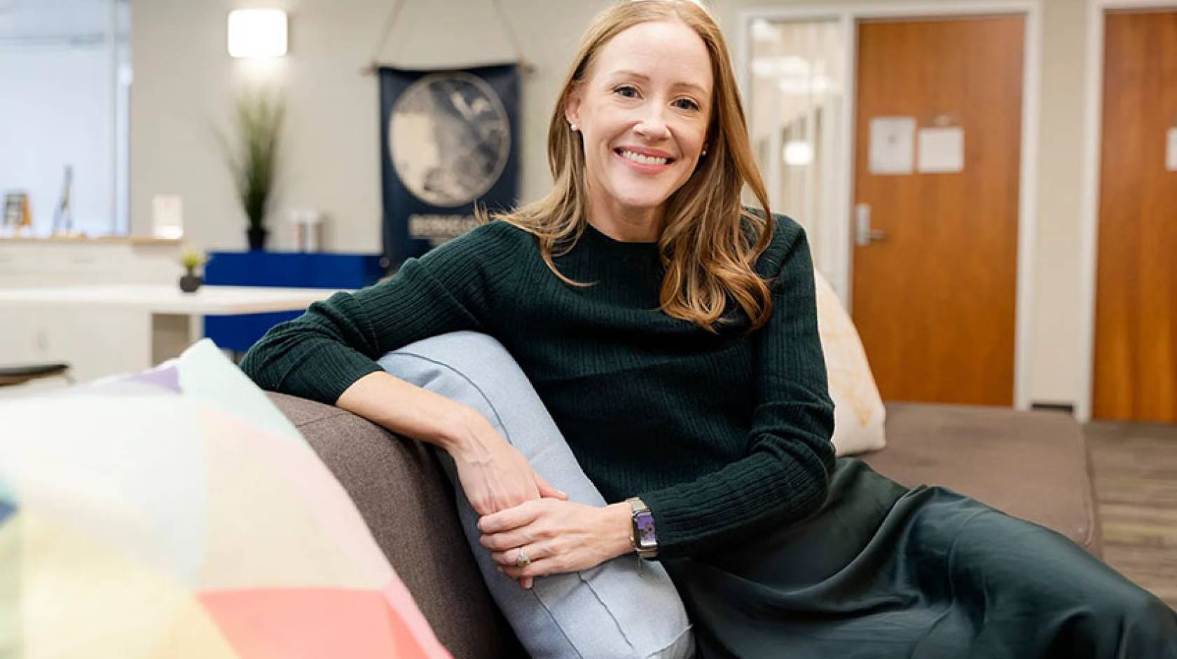 Brandie Nonnecke, seated on a couch, smiling at the viewer