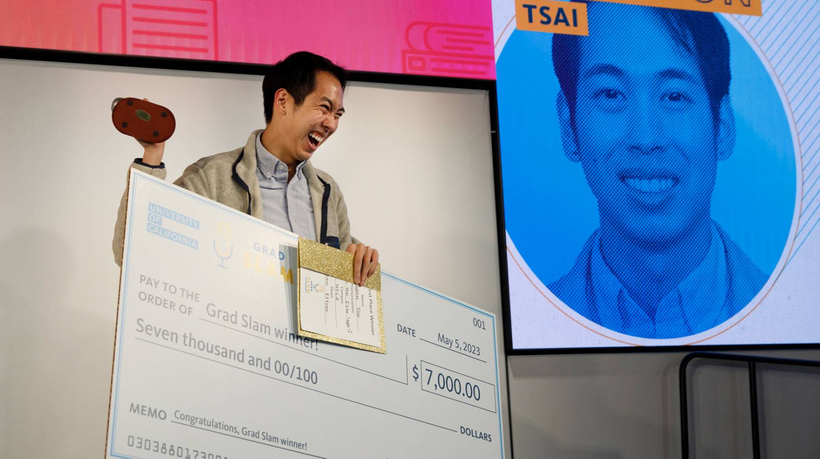 Brandon Tsai holds up the trophy, the Slammy, and his winning check at UC Grad Slam 2023