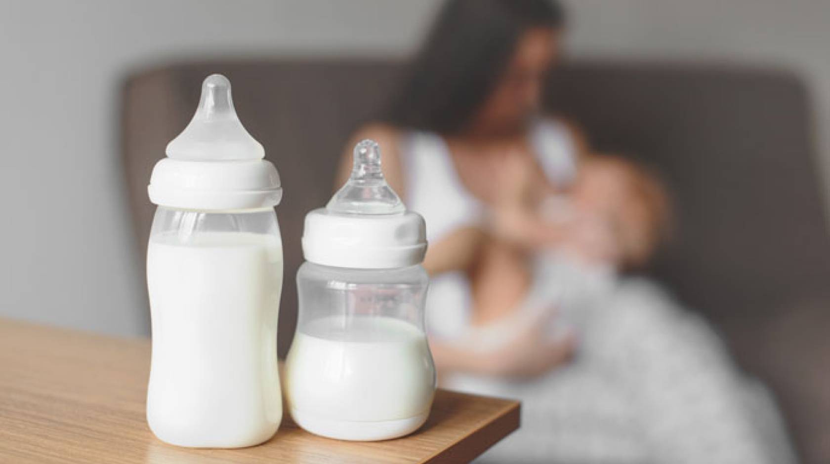 Breastmilk bottles in front of a mother breastfeeding