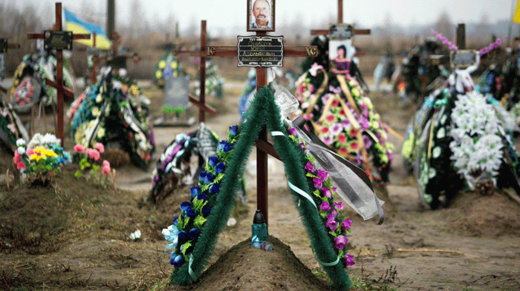 Photos on crosses covered in flowers mark graves in Bucha, Ukraine