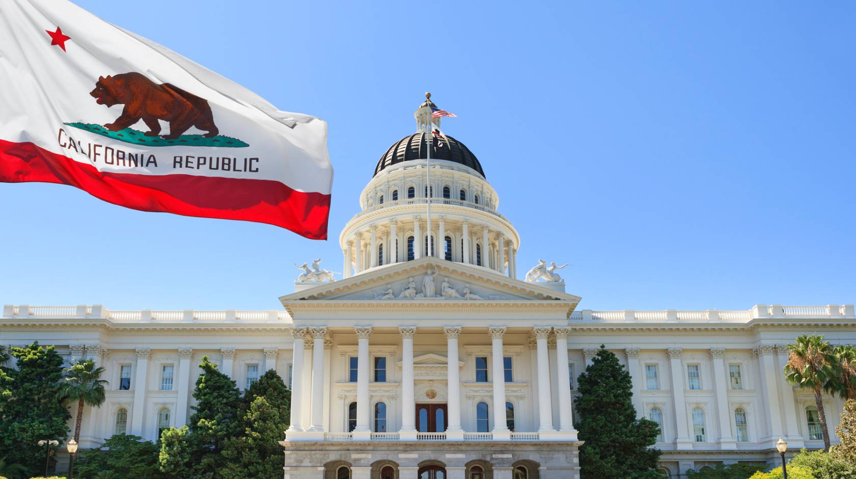 Sacramento capitol building with California state flag flying in front of it