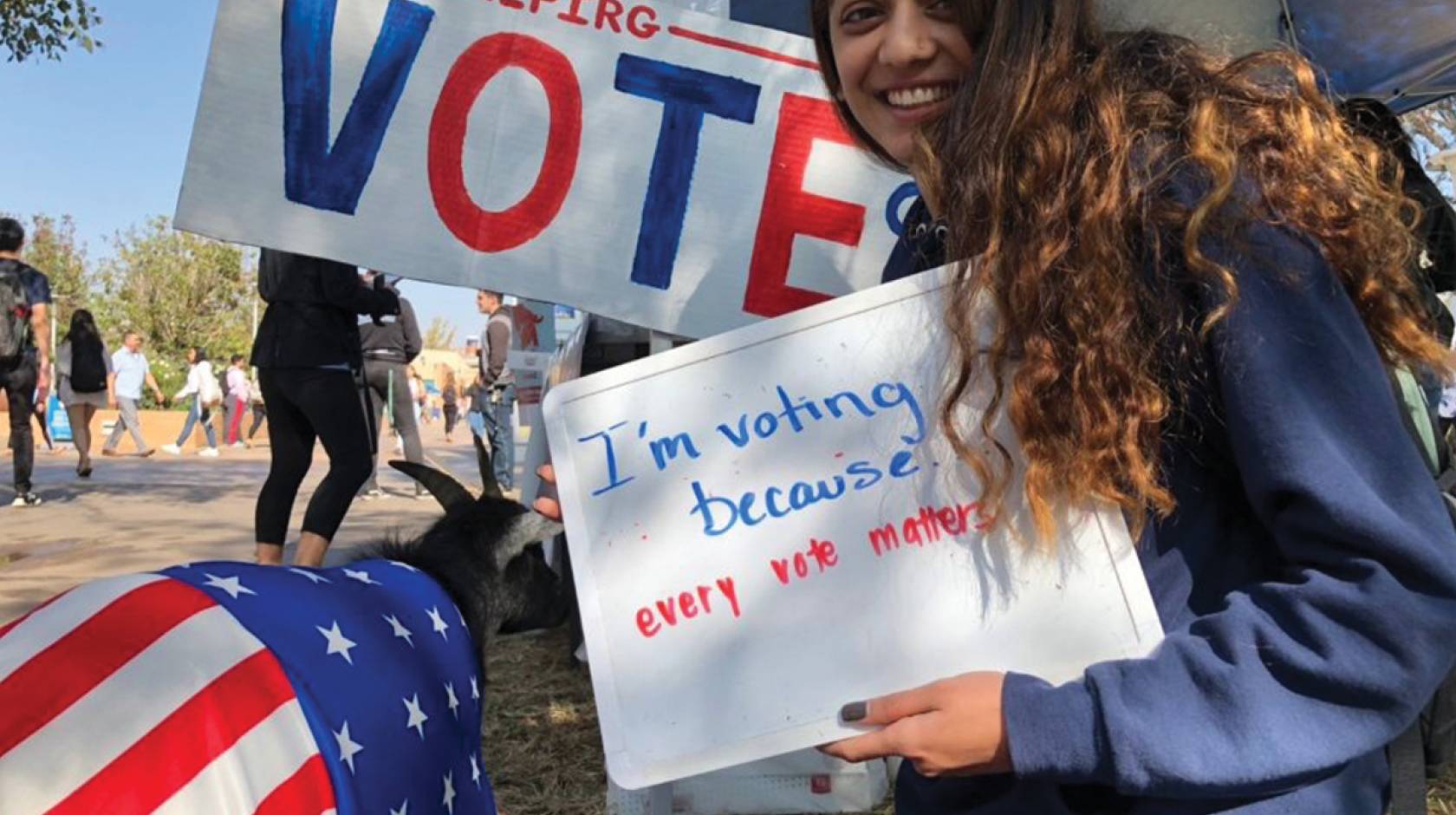 UC Riverside young woman student holds a vote sign next to the vote goat