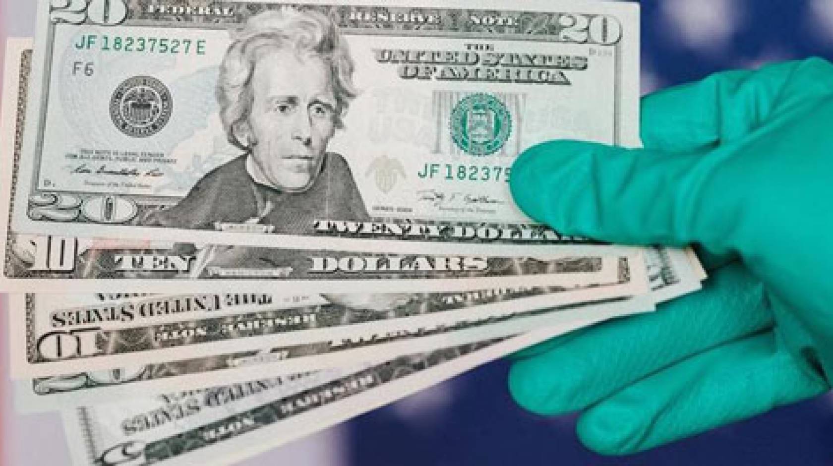Gloved hand holding $20 bills