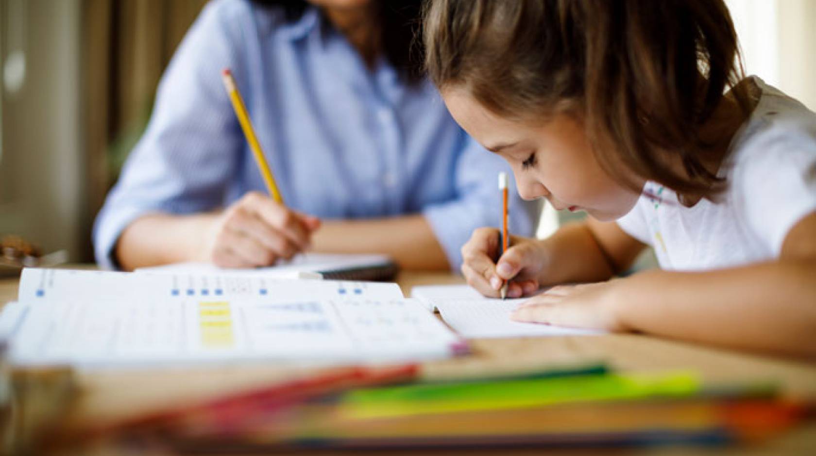 Young child doing homework with her mother