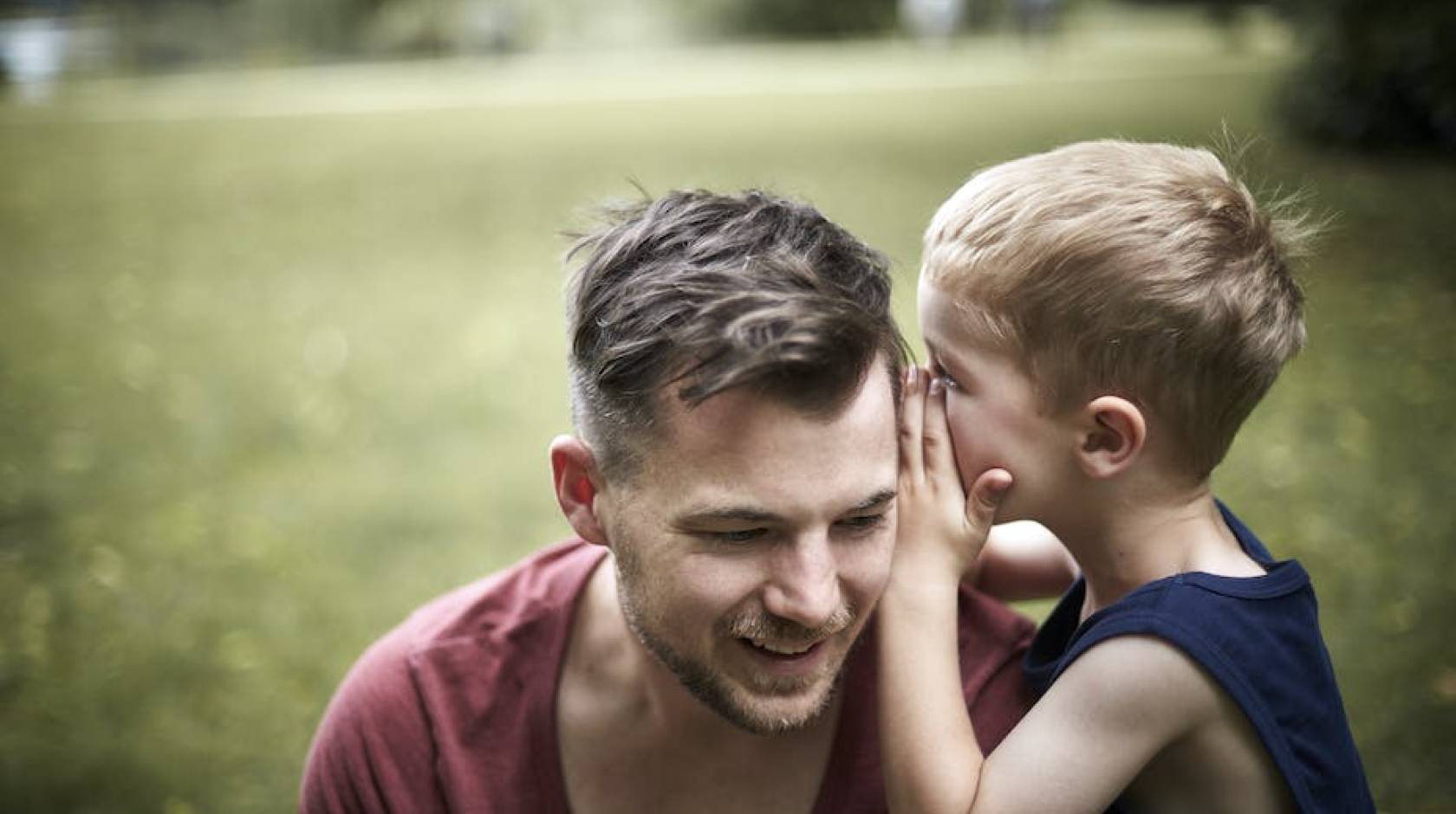 Child whispering in father's ear