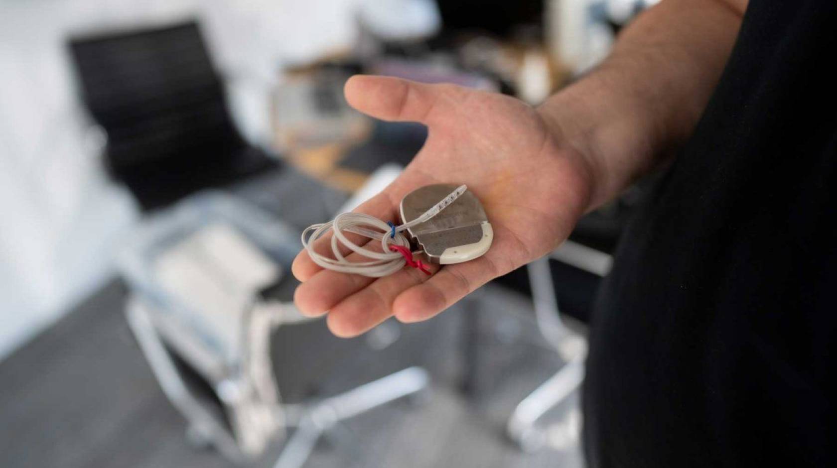 A patient holds a deep brain stimulation device in his hand.