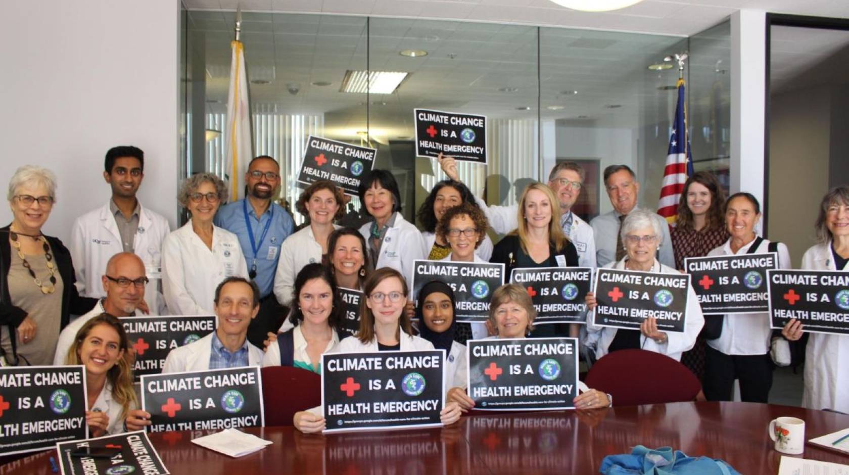 Varied group of people holding up climate change is a health emergency signs